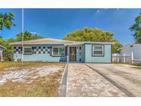 Charming single-story home featuring a colorful facade, brick walkway, and well-maintained landscaping at 3045 Stratford Dr, Largo, FL 33771