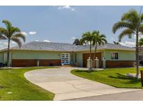 Charming single-story home features a circular driveway, well-manicured lawn, and lush tropical landscaping at 600 Eleuthera Dr, Punta Gorda, FL 33950