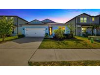 Charming single Gathering home boasting lush landscaping, a paver driveway, and an attached two-car garage at 6398 Bradford Woods Drive, Zephyrhills, FL 33542