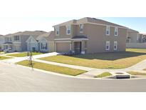 Two-story tan home on a corner lot featuring a well-manicured lawn and attached two-car garage at 7530 Broad Pointe Dr, Zephyrhills, FL 33540