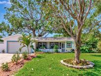 Charming single-story home with a well-manicured lawn, beautiful trees, and a cozy screened-in porch at 8326 40Th N Pl, St Petersburg, FL 33709
