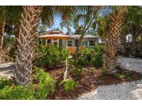 Charming home with tropical landscaping, featuring palm trees and a cozy seating area with an umbrella at 8403 W Gulf Blvd, Treasure Island, FL 33706