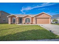 Charming single-story home features a manicured lawn, arched windows and a two-car garage at 10841 Standing Stone Dr, Wimauma, FL 33598