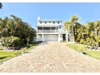 Beautiful coastal home with a brick drive, lush landscaping, and screened in porch perfect for relaxing at 16204 3Rd E St, Redington Beach, FL 33708
