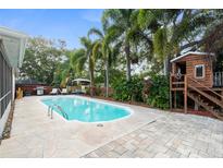 Backyard pool with a charming playhouse, patio, and lush tropical landscaping create a private outdoor retreat at 1686 Spottswood Cir, Palm Harbor, FL 34683