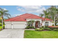 Charming single-story home with a red tile roof, lush landscaping, and a three-car garage at 18002 Forest Retreat Ln, Tampa, FL 33647
