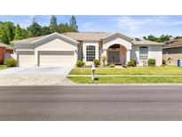 Charming single-story home with a three-car garage, manicured lawn, and inviting curb appeal at 28451 Great Bend Pl, Wesley Chapel, FL 33543