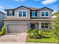 Beautiful two-story home showcasing a manicured lawn, paver driveway, and a welcoming gray exterior at 33263 Sycamore Leaf Dr, Wesley Chapel, FL 33545