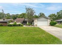 Charming single-story home with a well-manicured lawn, brick facade, and inviting curb appeal at 34527 Cedarfield Dr, Dade City, FL 33523