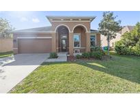 Charming stucco home featuring a two-car garage, arched entryway, and well-manicured lawn at 5108 Suncatcher Dr, Wesley Chapel, FL 33545