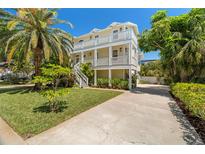 Stunning three-story beach house with a spacious driveway and tropical landscaping at 6113 Kipps Colony W Dr, Gulfport, FL 33707