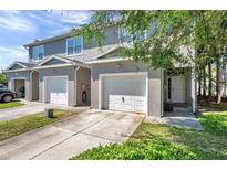 Gray townhome with attached garage and small yard, providing curb appeal and convenient parking at 7070 Opal Dr, Largo, FL 33773
