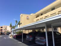 Exterior shot of condominium building featuring covered parking spaces and vibrant tropical landscaping at 7465 Bay Island S Dr # 211, South Pasadena, FL 33707