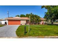 Charming single-story home with lush landscaping, stone accents, and an orange garage door at 1469 S Hillcrest Ave, Clearwater, FL 33756