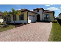 Beautiful yellow house featuring a brick driveway, 2-car garage, and well-maintained landscaping with a palm tree at 2217 5Th E St, Palmetto, FL 34221