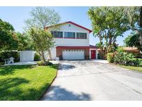 Two-story home featuring red roof, two-car garage, landscaped front yard, and mature trees at 3302 W Caracas St, Tampa, FL 33614
