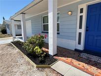 Charming front porch with a blue door, colorful mosaic tile, and newly landscaped flower beds at 3309 Rock Royal Dr, Holiday, FL 34691