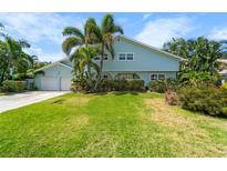 Charming two-story home featuring a lush green lawn, tropical landscaping, and a two-car garage at 4912 W Bay Way Dr, Tampa, FL 33629