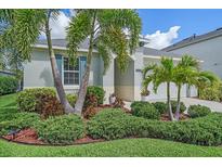 Charming home featuring beautiful landscaping with palm trees and lush green bushes at 7338 Milestone Dr, Apollo Beach, FL 33572