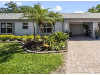 Charming single-story home with lush tropical landscaping, palm trees and paved driveway at 8244 Brentwood Rd, Seminole, FL 33777