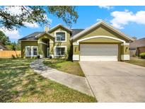 Charming two-story home with an attached two-car garage, green grass, and a walkway leading to the front door at 9603 Sunnyoak Dr, Riverview, FL 33569