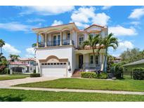 Elegant two-story home with a tile roof, balconies, lush landscaping, and a paver driveway at 108 Bermuda Ave, Tampa, FL 33606