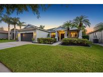 Charming home exterior featuring a well-manicured lawn, landscaped garden, and a two-car garage at 10922 Holly Cone Dr, Riverview, FL 33569
