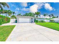 Charming single-story home featuring a well-manicured lawn and a long driveway leading to an attached garage at 11035 Huron Rd, St Petersburg, FL 33708