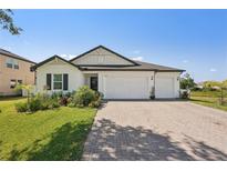 Charming single-story home featuring a three-car garage, brick driveway, and beautifully landscaped front yard at 13355 Palmerston Rd, Riverview, FL 33579