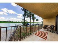 Enjoy this home's balcony with a view of the boat dock, lush landscape, and waterfront at 18201 Gulf Blvd # 201, Redington Shores, FL 33708