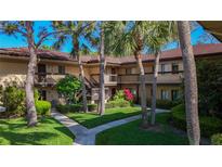 Exterior view of a two-story condo building, with lush landscaping and tropical trees at 2685 Sabal Springs Cir # 201, Clearwater, FL 33761