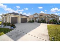 Spacious home featuring a large driveway, three-car garage, stone accents, and manicured landscaping at 5325 San Remo Cir, Wimauma, FL 33598