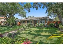 Charming single-story home featuring a lush front lawn, vibrant landscaping, and a welcoming walkway leading to the front door at 6213 10Th S Ave, Gulfport, FL 33707