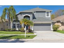 Charming two-story home featuring a manicured lawn, gray facade, arched entryway, and a two-car garage at 7725 Bingham Ct, Tampa, FL 33625