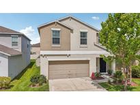 Charming two-story home featuring tan exterior, a two-car garage and manicured front lawn at 17331 White Mangrove Dr, Wimauma, FL 33598
