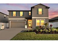 Beautiful two-story home featuring a well-manicured lawn, colorful landscaping, a two-car garage, and decorative exterior shutters at 36454 Flats St, Zephyrhills, FL 33541
