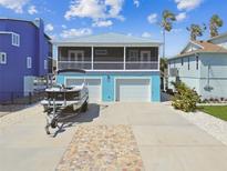 Charming two-story home featuring a screened-in porch, a two-car garage, and a boat on a trailer in the driveway at 4039 Casa Ct, Hernando Beach, FL 34607