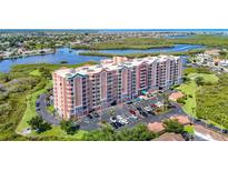 Multi-story condo building with a beautiful surrounding landscape and a parking lot full of cars at 4516 Seagull Dr # 903, New Port Richey, FL 34652