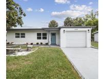 Charming single-story home featuring a well-maintained lawn, a one-car garage, and a serene blue front door at 5312 Berkley Rd, New Port Richey, FL 34652