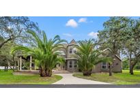 Stunning two-story home featuring a turret, large arched window, brick-lined entryway, mature landscaping and elegant curb appeal at 15053 Peace Blvd, Spring Hill, FL 34610