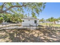 Charming single-story home with a fenced yard, mature shade tree and a clear blue sky at 1540 7Th E Ave, Bradenton, FL 34208