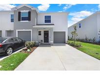 Two-story townhome showcasing a gray and white exterior with a driveway and an attached garage at 32978 Tulip Petal Ln, Wesley Chapel, FL 33545