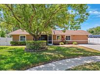 Charming single-story home featuring a lush front yard with mature landscaping and a welcoming screened entrance at 506 Spring Tree Ct, Tarpon Springs, FL 34689