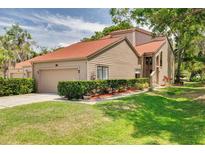 Inviting two-story home with a well-manicured lawn and lush landscaping, including mature trees at 60 Woodridge Cir, Oldsmar, FL 34677