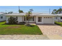 Charming single-story home featuring a brick driveway, a one-car garage, and a well-manicured lawn at 10036 40Th N St # 3, Pinellas Park, FL 33782