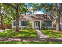 Charming home featuring a well-manicured lawn, beautiful trees, and classic architecture with eye-catching blue shutters at 1905 Mckinley St, Clearwater, FL 33765