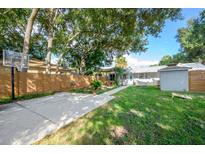 Spacious backyard featuring a basketball court, patio area, and lush greenery, perfect for outdoor activities and entertaining at 3905 N Highland Ave, Tampa, FL 33603