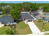 An aerial view of a modern home with a dark roof, a manicured lawn, and a long driveway at 4021 Ohio Ave, Tampa, FL 33616
