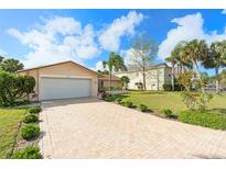 Charming single-story home with a brick driveway and a well-manicured lawn surrounded by lovely palm trees at 4120 Marine Pkwy, New Port Richey, FL 34652