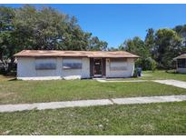 A single-story home showing boarded up windows and front yard at 9355 Pinero St, Spring Hill, FL 34608
